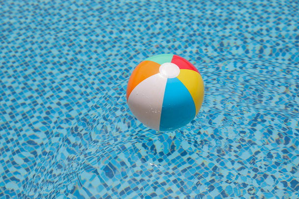 Plážový míč v bazénu. Barevný nafukovací míč plovoucí v bazénu, letní dovolená koncept. - Fotografie, Obrázek