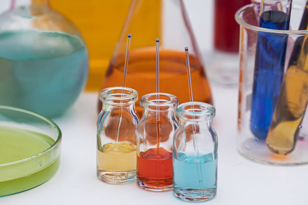 Скляні флакони з кольоровою лікарською рідиною з капілярами. Червоні, жовті та сині розчини в скляному флаконі в хімічній лабораторії
. - Фото, зображення