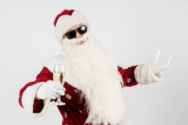 Koncept Vánoc a Nového roku. Santa Claus gestikuluje se sklenicí v ruce. Izolované pozadí. - Fotografie, Obrázek