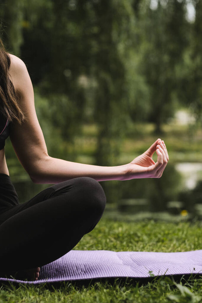 Yoga en el parque. Mujer en posición de loto al aire libre, gesto de mano de yoga. concepto de estilo de vida saludable - Foto, imagen