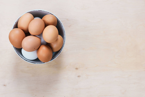 Eier lagen auf hölzernem Hintergrund. Lebensmittelzutat. Nahaufnahme roher Hühnereier in Schale auf Holzgrund. - Foto, Bild