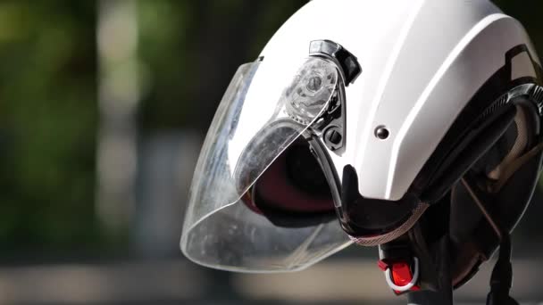 Valkoinen moottoripyöräkypärä pysäköidyllä moottoripyörällä tien vieressä. Pyörä kuljettaja suojelija - Materiaali, video