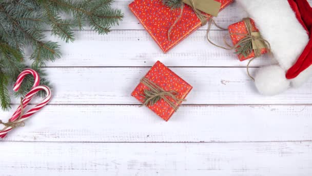 Una scatola regalo che avvolge la carta rossa appare sullo sfondo di legno e la mano femminile raccoglie un regalo. Piatto. Addobbi natalizi. Concetto di regali di anno nuovo, shopping festivo e festivo. - Filmati, video