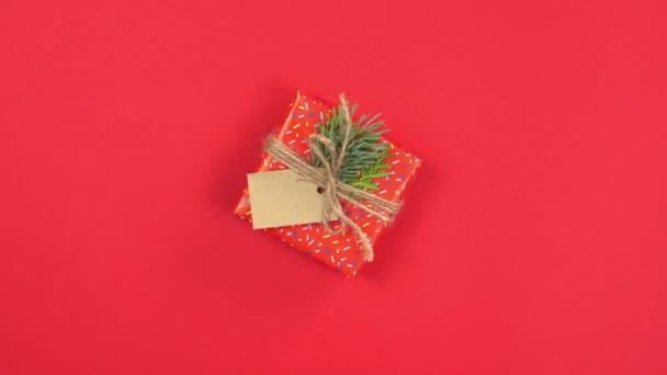 Szilveszter és karácsony bemutatja 360 fokos forgás, kézzel készített ajándékdobozok csomagolva piros papírral és díszített fenyő ágak, lapos fektetés, piros háttér. Másold a helyet. Fogalma üdvözlő kártya. Felülnézet. - Felvétel, videó