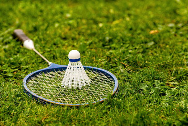 Badminton rackets and shuttlecock on green grass - Fotó, kép