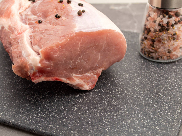 Ακατέργαστο χοιρινό κρέας σε μαρμάρινο ταμπλό με θέα τα μπαχαρικά - Φωτογραφία, εικόνα