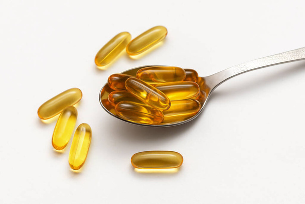 fish oil capsules in spoon on white background - Foto, afbeelding