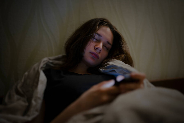 La mujer se durmió en la cama con un teléfono en las manos - Foto, imagen