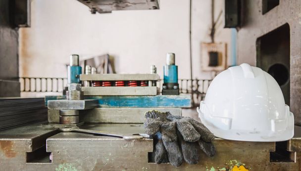 Un casque blanc pour la sécurité de l'ingénieur d'usine et ouvrier qui est mis sur la machine de travail des métaux et ont des gants et une clé à côté. - Photo, image