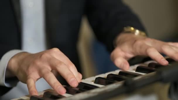 Músico tocando en las teclas de piano sintetizador de teclado. El músico toca un instrumento musical en el escenario del concierto. De cerca. Un fondo de instrumentos de música.  - Metraje, vídeo
