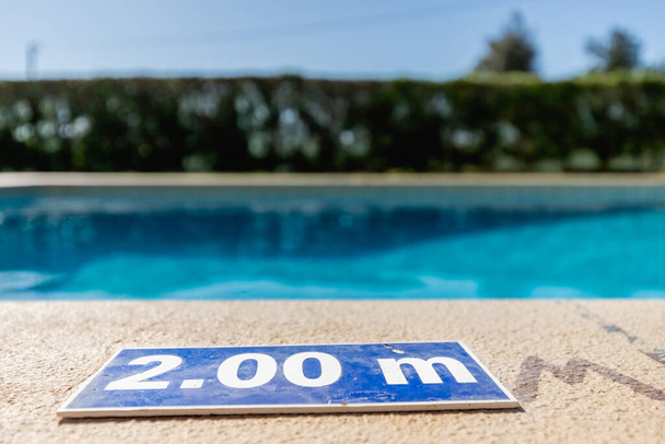 синя пластикова тарілка на краю басейну, що вказує на глибину 2,00 метрів
 - Фото, зображення
