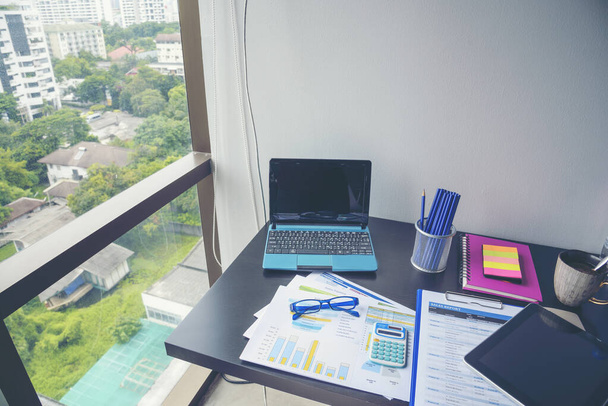 Офисный ноутбук бизнес-график финансовых документов и график на деревянном столе с чашкой кофе. Плоский ноутбук лежал на рабочем столе. Нет людей бизнес-график макет графика на рабочем месте бизнеса - Фото, изображение