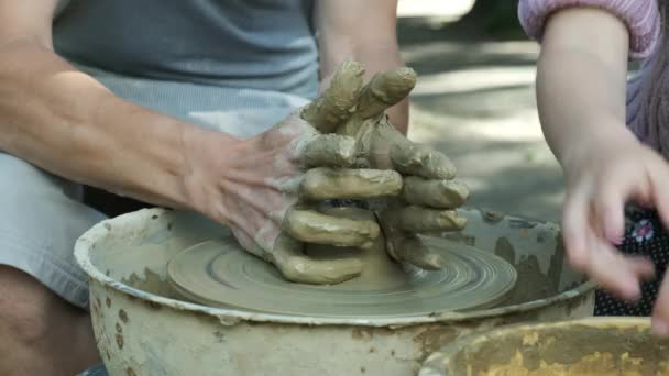 Meester leert meisje om aardewerk te maken van klei. Roterend Pottenbakkerswiel. close-up - Video