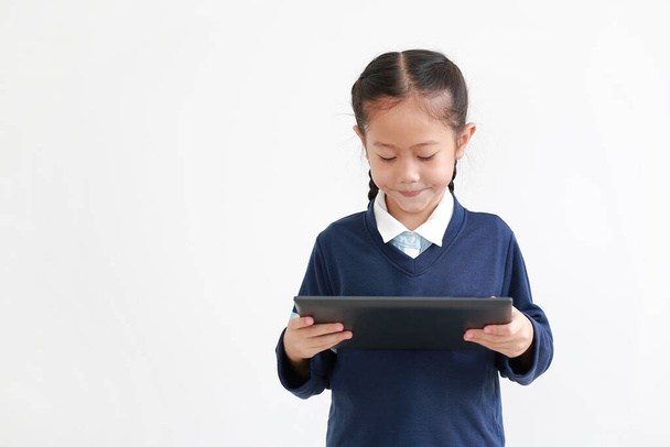 Portrait of asian little child girl in school uniform using tablet isolated on white background. Studio shot - Foto, Imagen