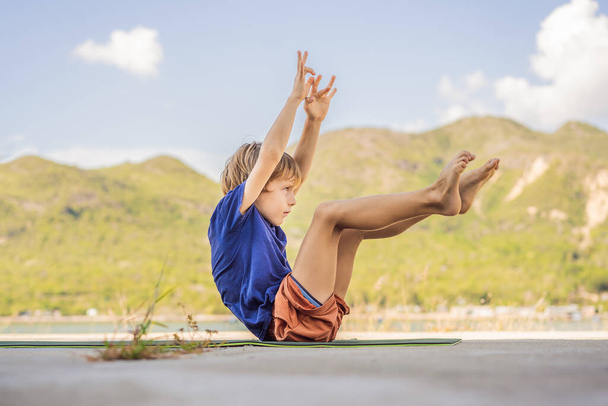 Boy doing yoga on a yoga mat against a background of mountains - Foto, Imagem