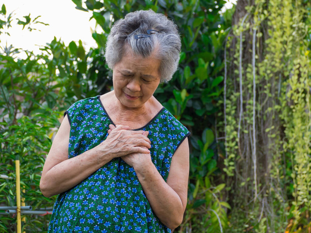 Портрет пожилой женщины с сердечным приступом. Старшая женщина хватается за грудь при первых признаках стенокардии, инфаркта миокарда или сердечного приступа. Концепция сердечного приступа. - Фото, изображение