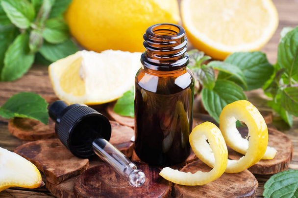 Lemon citrus fruit essential oil and mint, aromatherapy oil natural organic cosmetic on rustic wood background. - 写真・画像