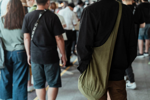 Image recadrée de l'homme en chemise noire debout parmi les gens à la station de skytrain. - Photo, image