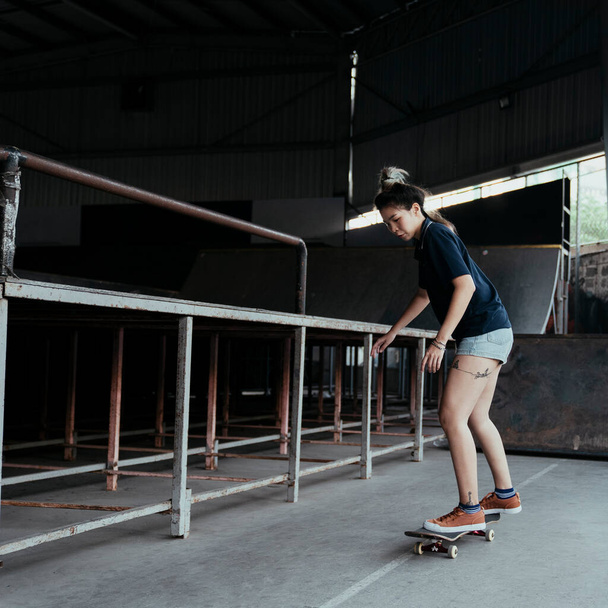Femme en polo bleu foncé glisse longboard sous ses pieds tout en jouant dans le temps libre dans le domaine du skateboard. - Photo, image