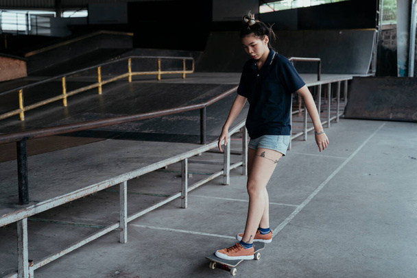 Žena v tmavě modré polo shirt slide longboard pod nohama, zatímco hraje ve volném čase na skateboard pole. - Fotografie, Obrázek