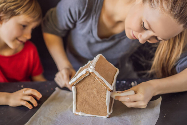 Young mother and kid making gingerbread house on Christmas eve - Foto, Imagem