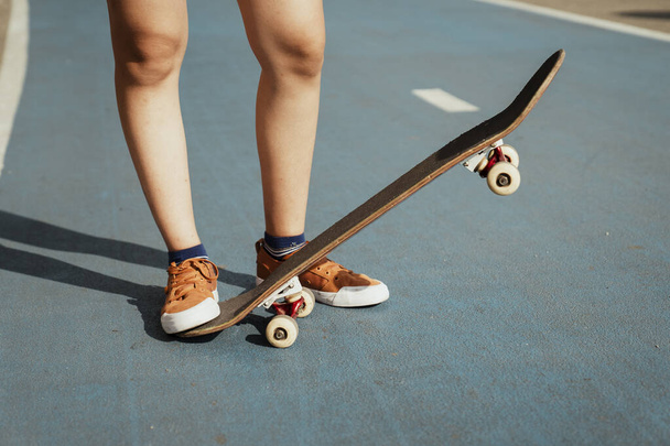 Immagine ritagliata delle gambe della donna mentre gioca longboard sulla parte blu con un lato verso il basso e un lato verso l'alto. - Foto, immagini
