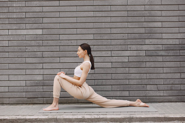 Woman practicing advanced yoga against a dark urban wall - Φωτογραφία, εικόνα