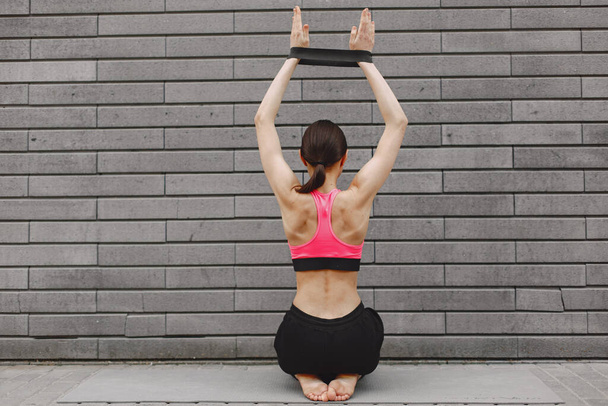 Woman practicing advanced yoga against a dark urban wall - 写真・画像