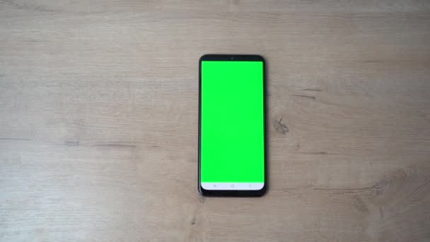 il telefono con lo schermo verde è sul tavolo di legno - Filmati, video