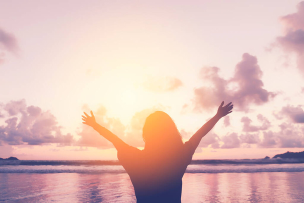 Щаслива жінка піднімає руку на тропічному пляжі з фоном неба заходу сонця. Подорожі відпочинок і свобода відчувають хорошу концепцію. Урожай тон фільтра стиль кольору
. - Фото, зображення