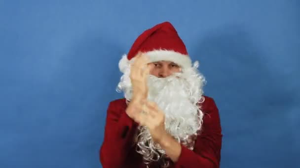 Un uomo come Babbo Natale balla su sfondo blu, timelapse. Natale e Capodanno concetto. Sconti e promozioni, vendite. Il tizio con la barba bianca e il cappello rosso. - Filmati, video