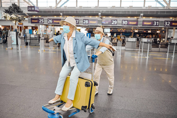 Ηλικιωμένος άντρας που κουβαλάει γυναίκα επιβάτη σε καρότσι αποσκευών - Φωτογραφία, εικόνα