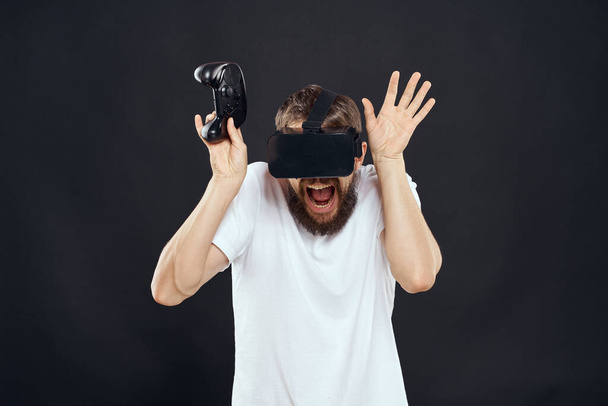 férfi visel virtuális valóság szemüveg gamepad a kezében technológia játékok szabadidő sötét háttér - Fotó, kép