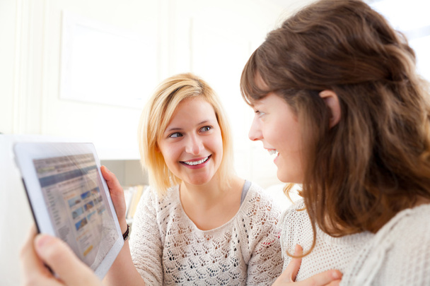 Girls choosing their holidays destination on tablet - Foto, Imagen