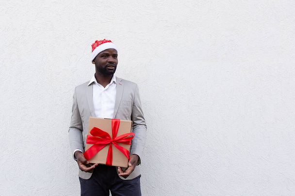 афроамериканець у новорічному капелюшку з подарунком. - Фото, зображення