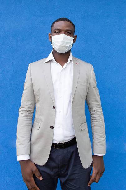 der Afroamerikaner in einer Schutzmaske auf blauem Hintergrund - Foto, Bild