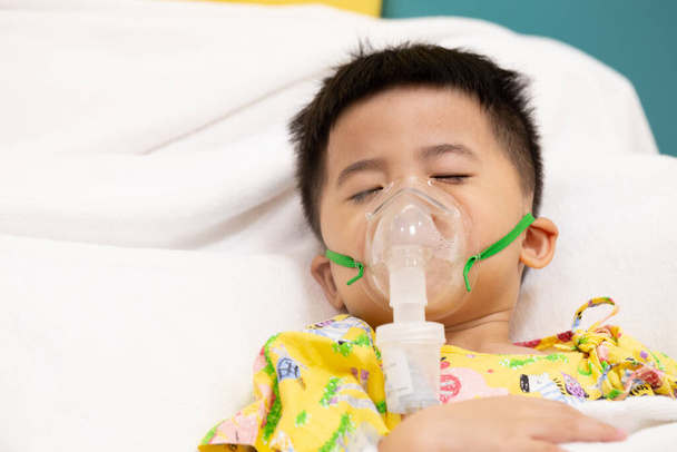 Asiatischer kleiner Junge beim Inhalieren mit Vernebler im Krankenhaus, Vernebelungskonzept - Foto, Bild
