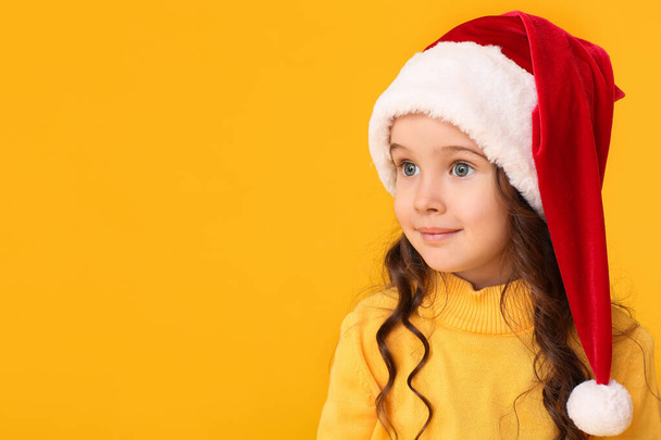 Cute little girl in Santa hat on color background - Fotoğraf, Görsel