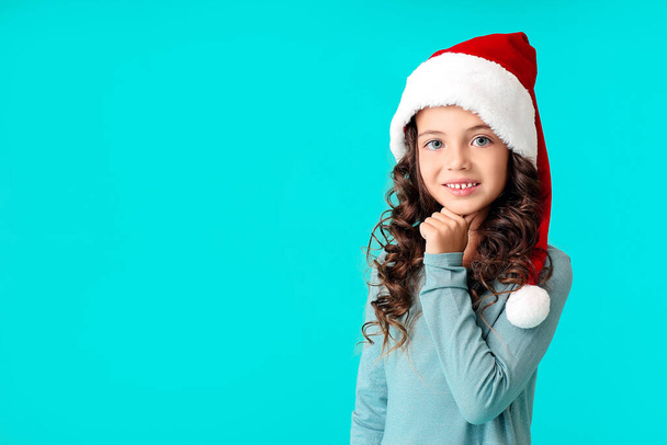 Cute little girl in Santa hat on color background - Zdjęcie, obraz