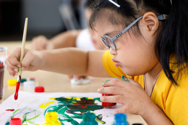 Lähikuva kuva Aasian tyttö Downin syndrooma maalaus taidekurssilla koulussa. Käsite vammainen lapsi oppiminen. - Valokuva, kuva