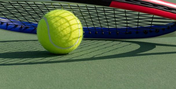 Bola de tênis e sombra raquete no campo de ténis duro verde fechar. Fundo desportivo. Foco seletivo, espaço de cópia - Foto, Imagem