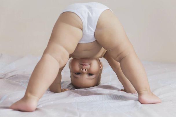 hermoso bebé en bragas blancas de pie sobre su cabeza - Foto, Imagen