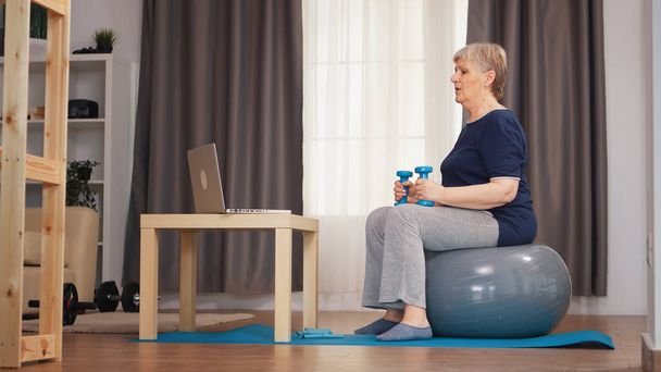 Oudere vrouw training met gewichten - Foto, afbeelding