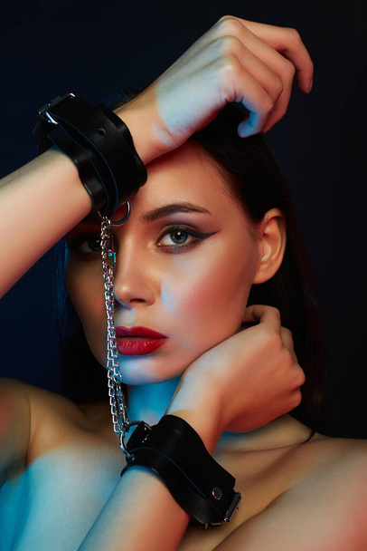 Girl in handcuffs. tied hands Beautiful young Woman in color lights - Foto, Imagen