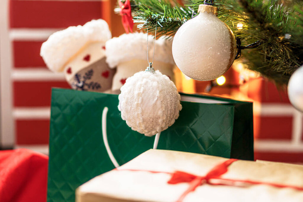 Xmas, winter, new year, Celebration, family, gift concept - Holiday atmosphere at home. Bright presents boxes under Christmas tree decorated with balls on background red fireplace with burning fire - Photo, Image