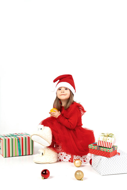 new years picture: a little girl in a Santa hat sits on gifts - Φωτογραφία, εικόνα