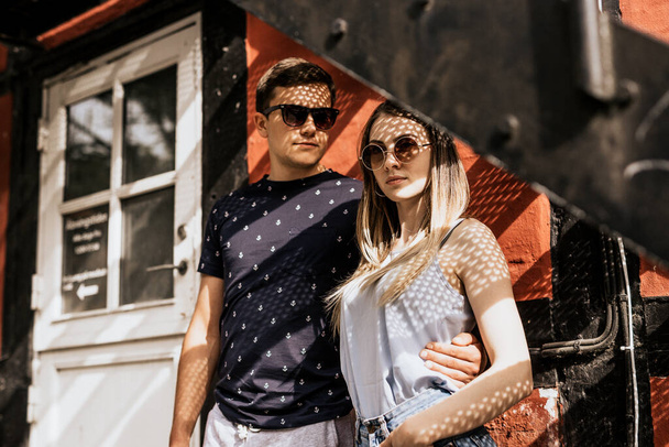Romantic couple stand and look in camera with shadow of sunlight . Serious man and woman on building background - Fotó, kép