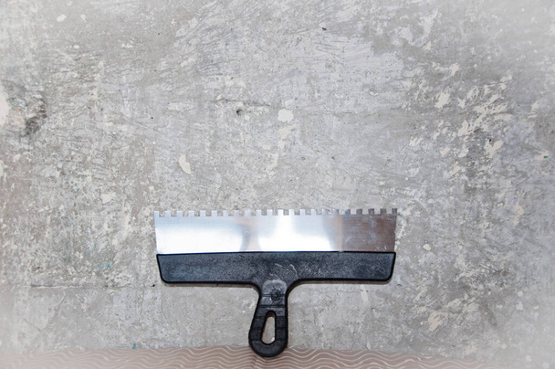 spatula for repair and construction. building concept. work tool and equipment. workplace. working with spackling. Damaged wall repair. putty knife on gray grunge cement wall background. - Photo, Image