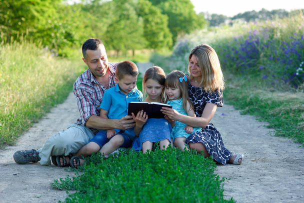 jeune famille heureuse lisant la Bible dans la nature - Photo, image