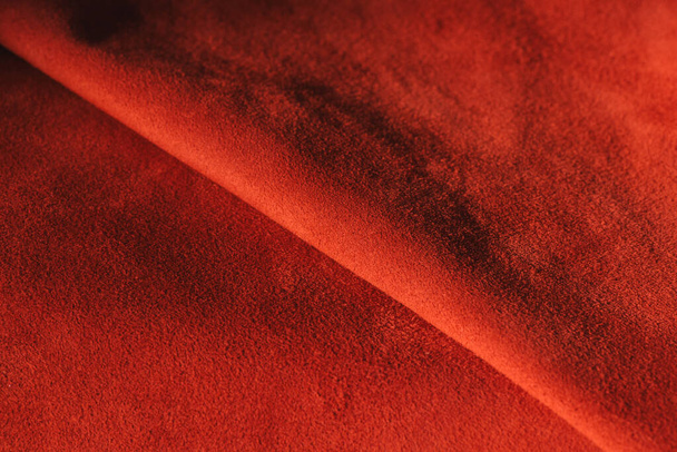 Red matte background of suede fabric, closeup. Velvet texture of seamless leather. Felt material macro. Red suede texture. Fabric, leather, material for designers. - Foto, Imagen